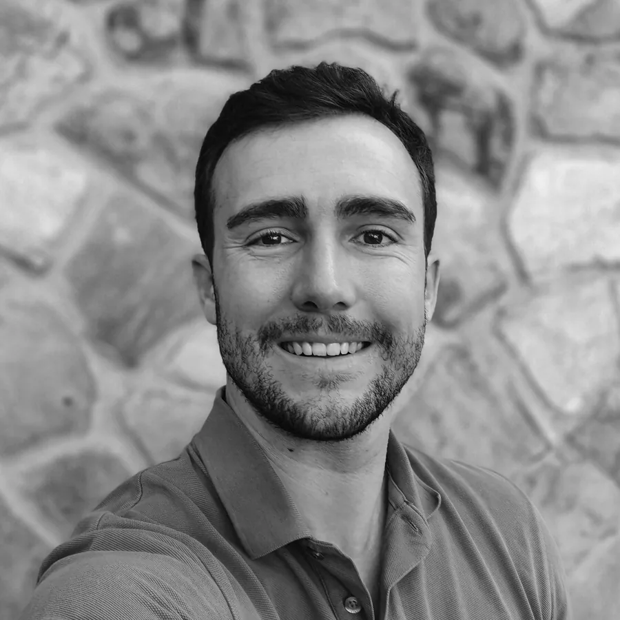 Retrato en blanco y negro de Luis Gómez Seisdedos sonriendo, con un muro de piedra de fondo.
